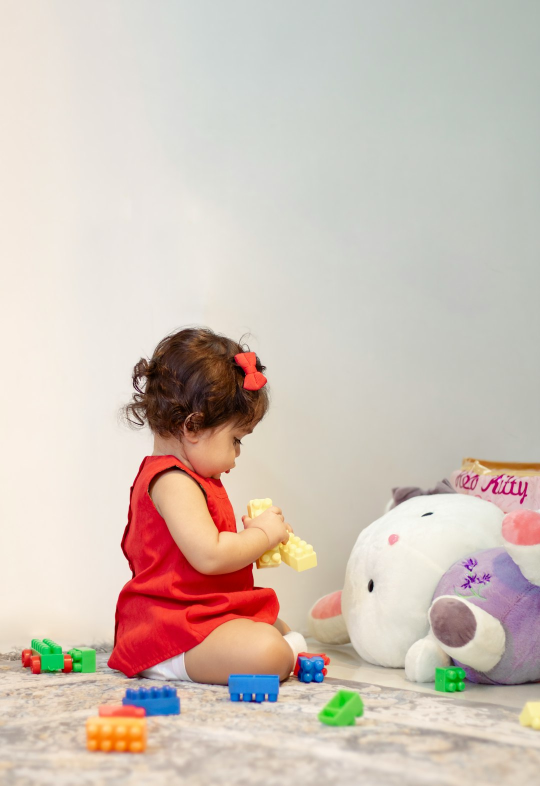 a-little-girl-in-a-red-dress-playing-with-a-stuffed-animal-bqchxfmv6km