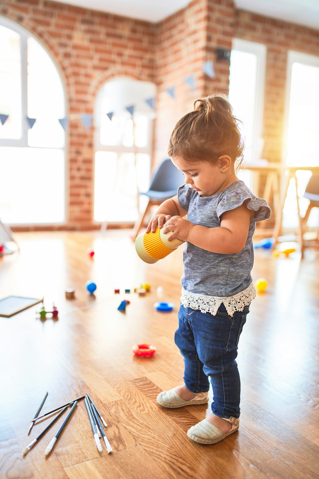 Beautiful toddler holding plastic glass at kindergarten